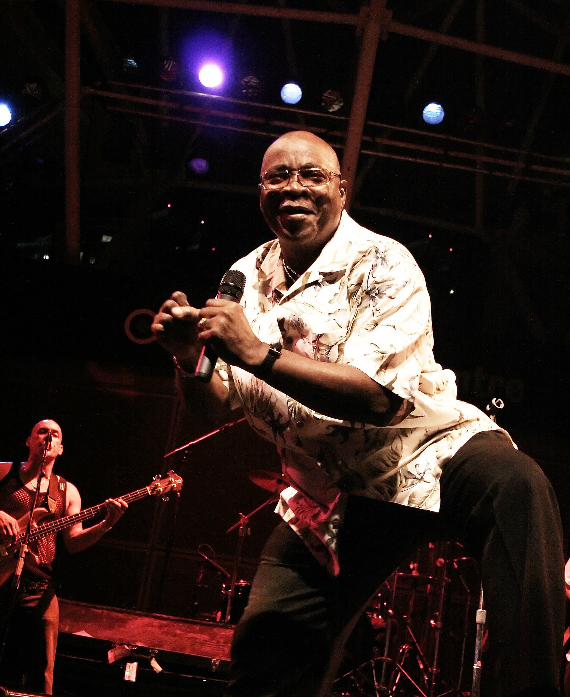 The Mighty Sparrow, in a patterned shirt, singing into a microphone on stage at Toronto's Harbourfront Centre in August 2006
